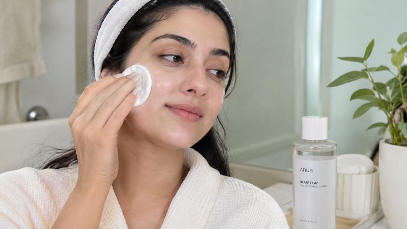 Woman applying toner to her face with a cotton pad after cleansing