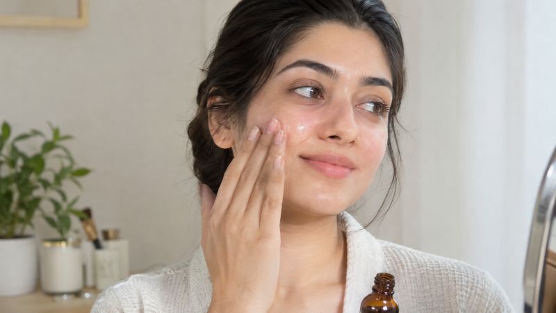 Woman checking skin discomfort after applying skincare serum